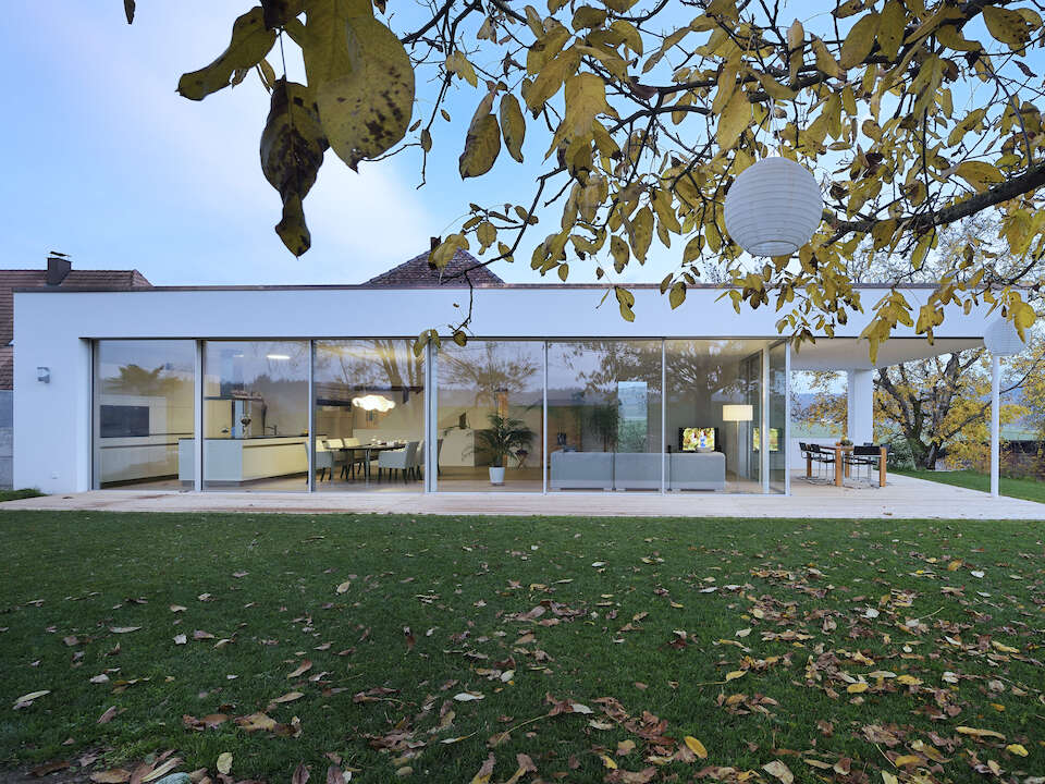 Glass house villa with large window façade opening out onto the garden